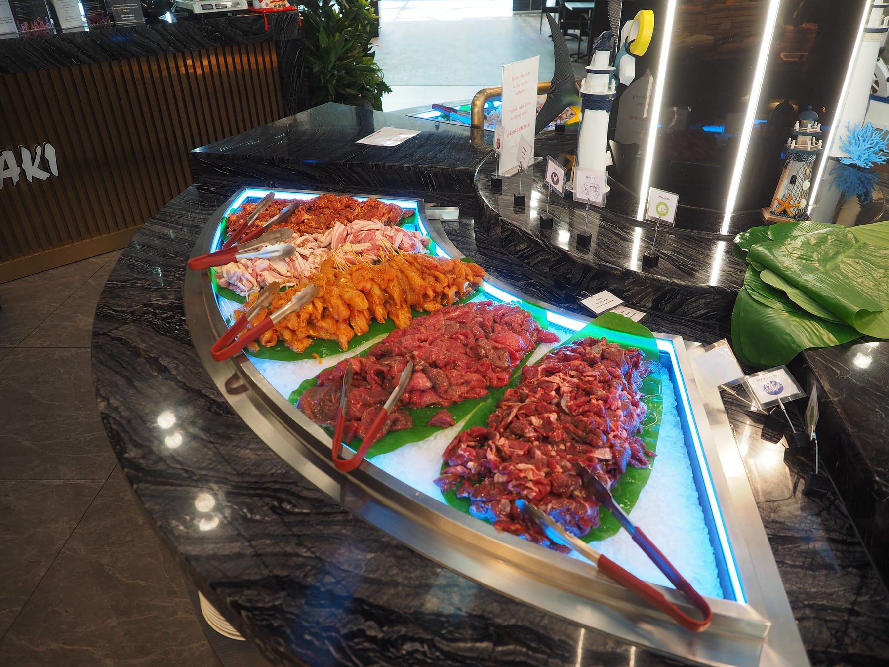 A buffet counter of sliced meats and seafood on ice